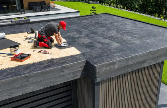 Professionnel effectuant l'application d'un enduit protecteur pour l'entretien toitures plates sur une structure moderne.