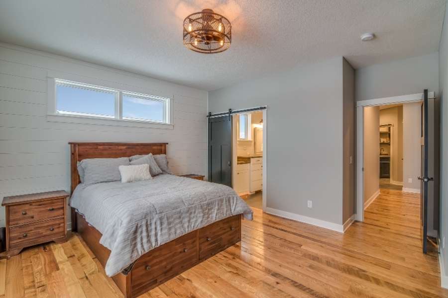 Chambre cocon douillet avec lit en bois massif, parquet clair et porte coulissante style grange