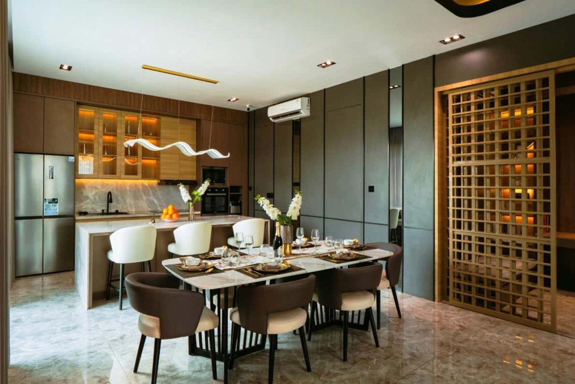 Une vue élégante et moderne d'une cuisine et d'une salle à manger décloisonnées avec un éclairage d'accentuation chaud.