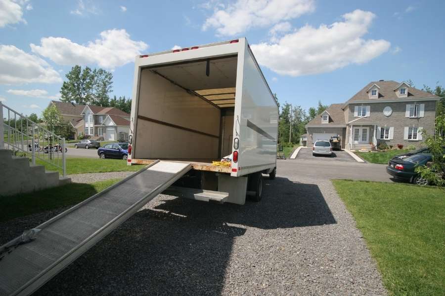 Un grand camion de transport ouvert avec sa rampe d'accès prêt pour un déménagement international.