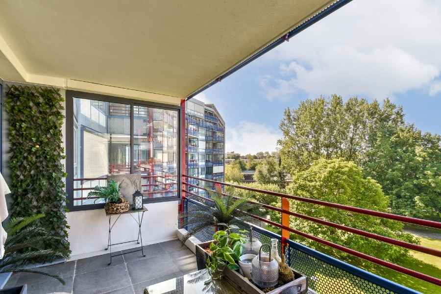 Un balcon d'appartement moderne avec un mur végétal et du mobilier en rotin pour une décoration tendance.