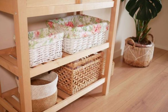 Une étagère en bois avec des paniers de rangement tressés et fleuris
