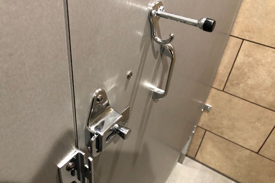 Un loquet à verrouillage rapide en métal chromé installé sur une porte de cabine, illustrant le type de serrure pour une porte de salle de bains.